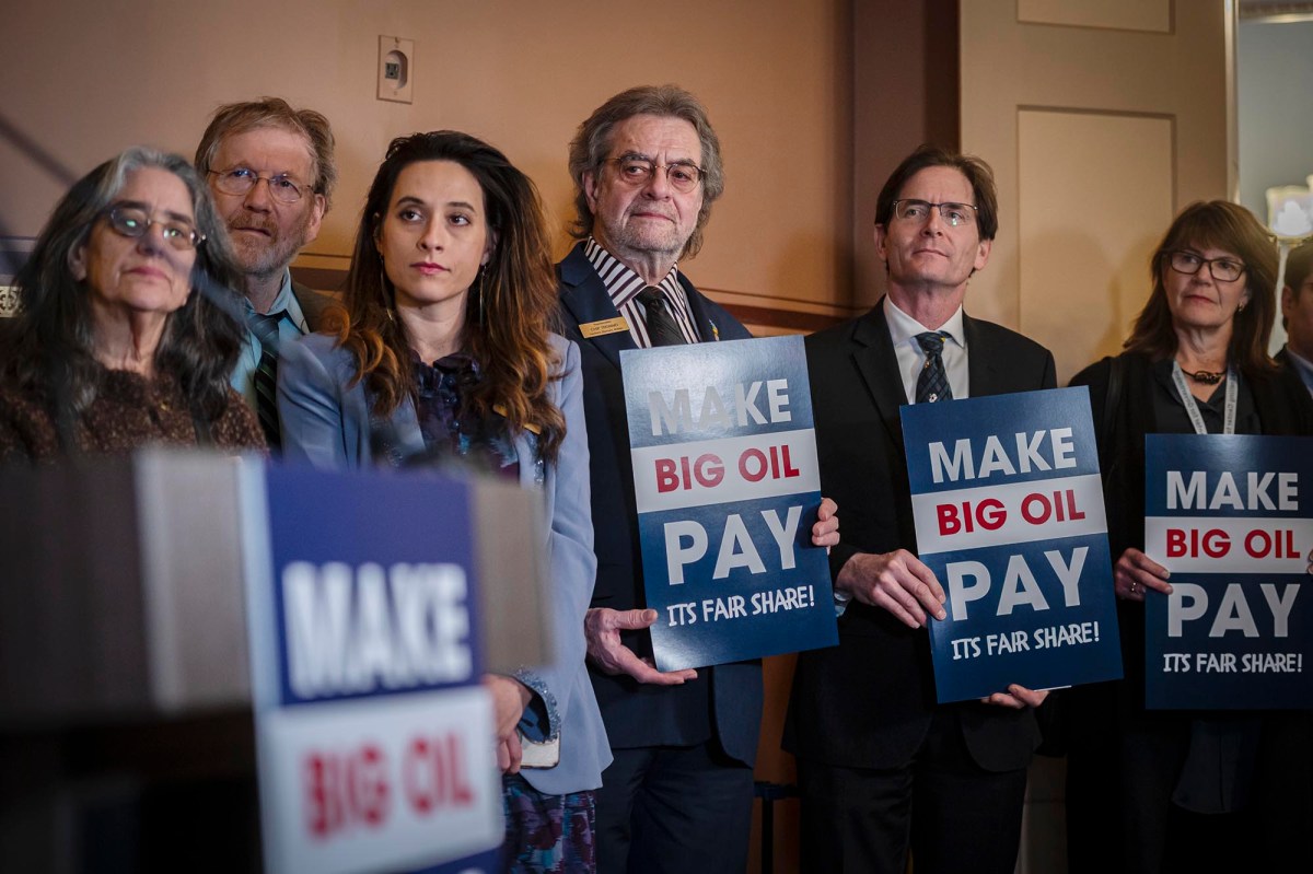 A group of people holding up signs that say make big oil pay.