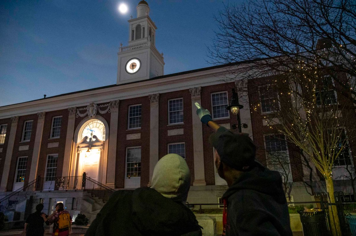 People standing outside a building at dusk with one person pointing towards the clock tower.