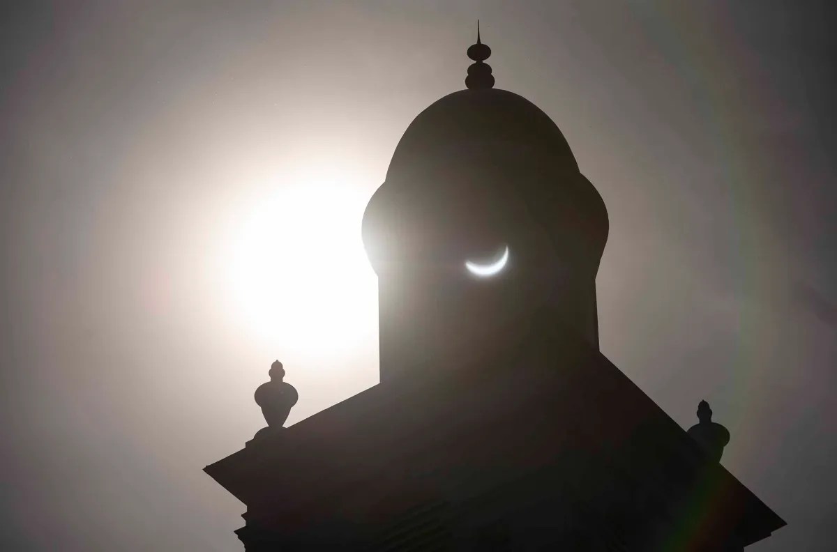 Silhouette of a building's dome against the backdrop of a solar eclipse.