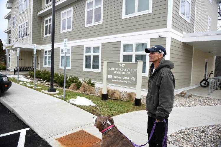 Man standing with a dog on a leash outside an apartment building labeled "747 Hartford Avenue Apartments.