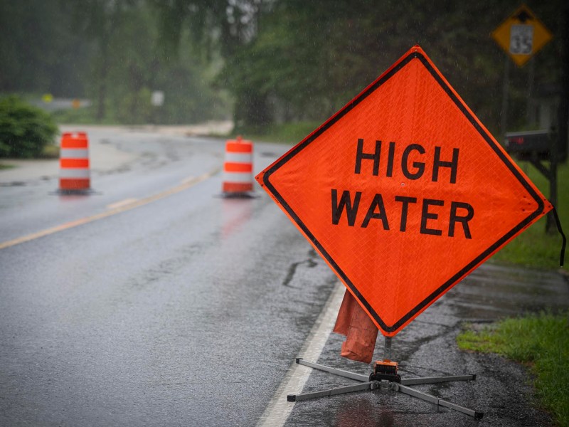 a high water warning sign on a wet road.