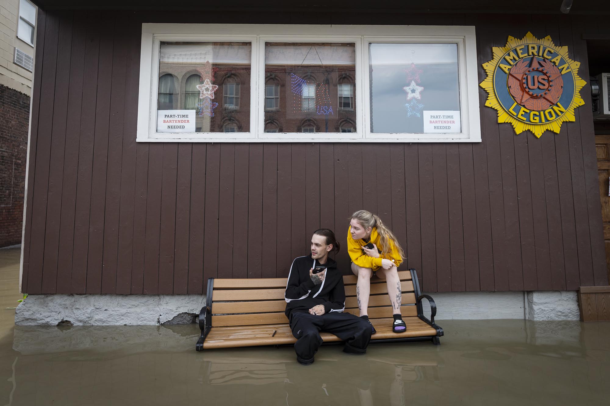 two people sitting on a bench in a flooded building.