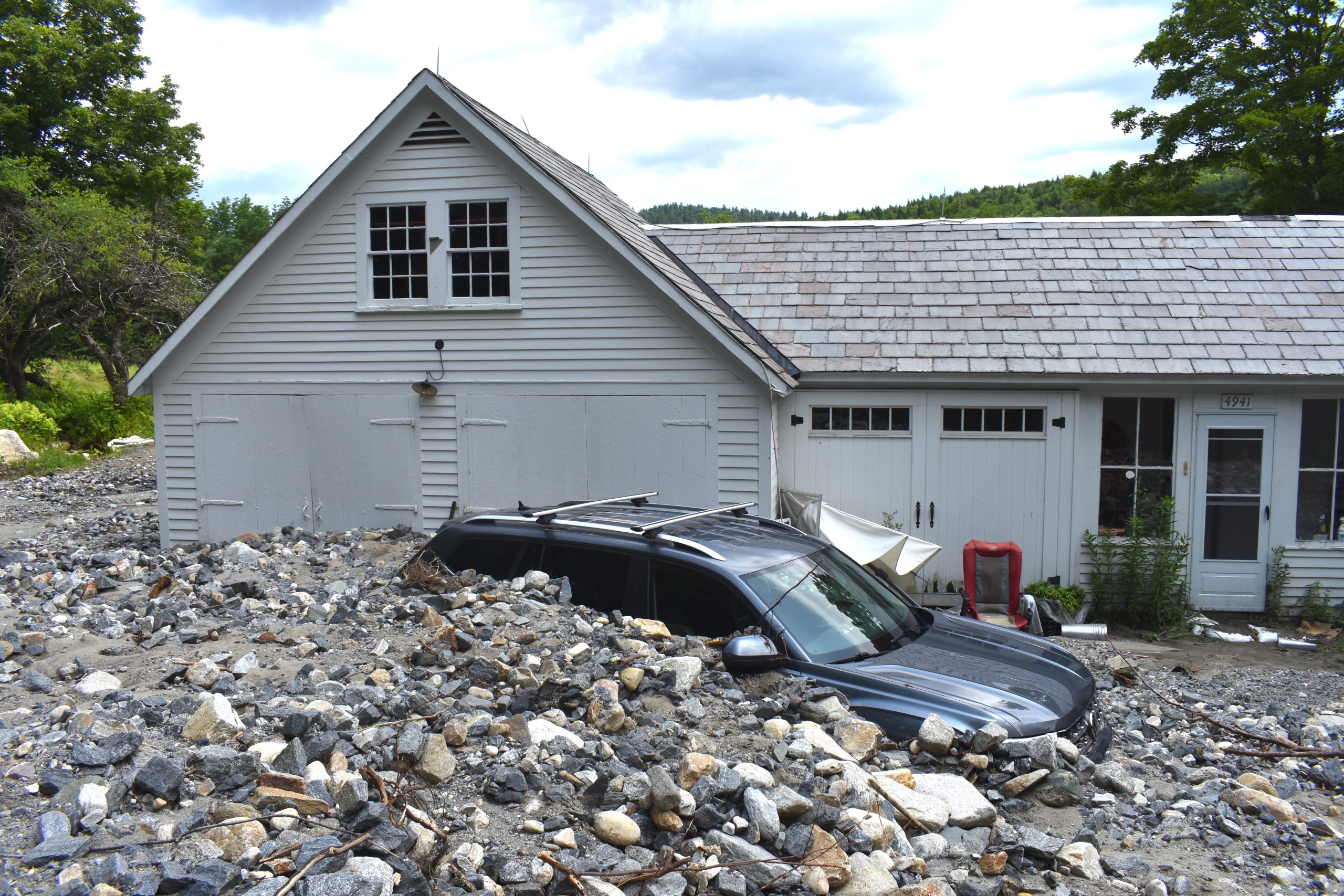 a SUV covered in rocks parked in front of a house.