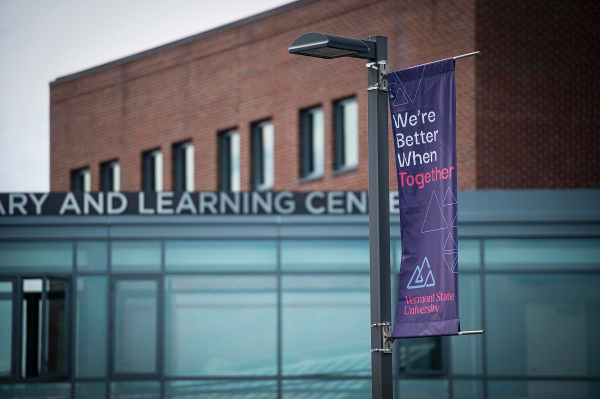 A banner reading "We’re Better When Together" hangs on a lamp post in front of a building labeled "Library and Learning Center" at Vermont State University.